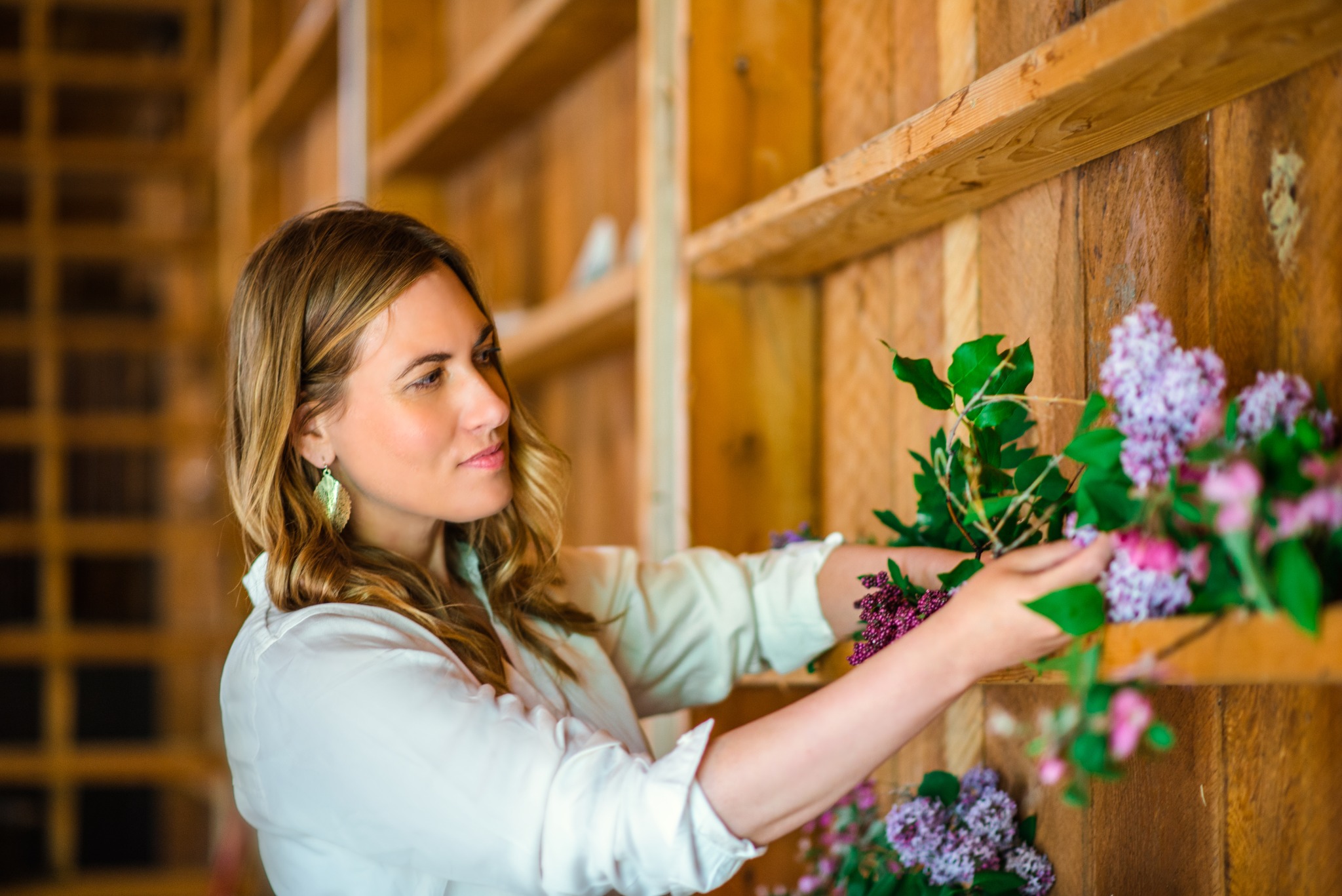 Dr. Michele Burklund arranging purple flowers against a warm wooden wall