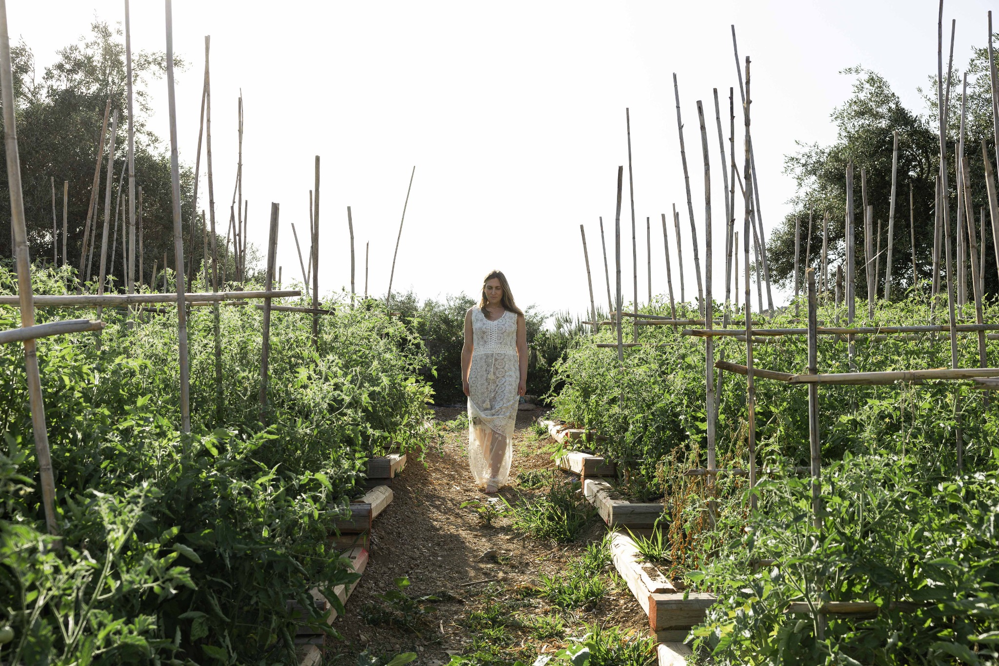 Dr. Michele Burklund walking through a lush garden in a white lace dress